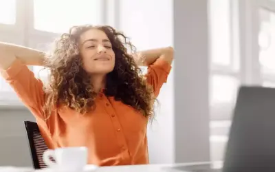 Femme souriante, mains derrière la tête, profitant d'une pause. Son retour congé maternité obligation employeur semble bien se passer.