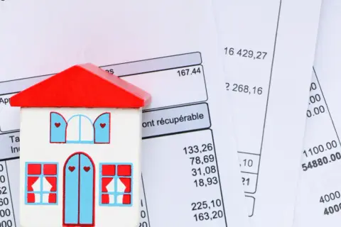 Maison en bois sur des factures. Apprenez comment calculer la taxe d'habitation.
