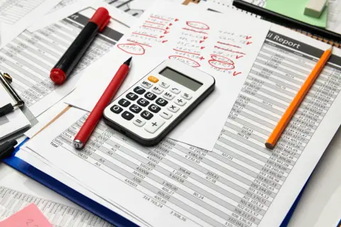 Calculatrice, stylos et feuilles de calcul. Préparation des comptes pour la taxe sur les salaires 2024.