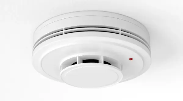 Détecteur de fumée blanc, rond, fixé au plafond. Un petit voyant rouge est allumé. Un détecteur fumée obligatoire pour votre sécurité.
