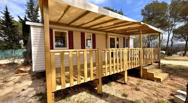 Mobil-home avec terrasse en bois sous un auvent, dans un cadre verdoyant. Une image qui pourrait illustrer la jurisprudence mobil-home.