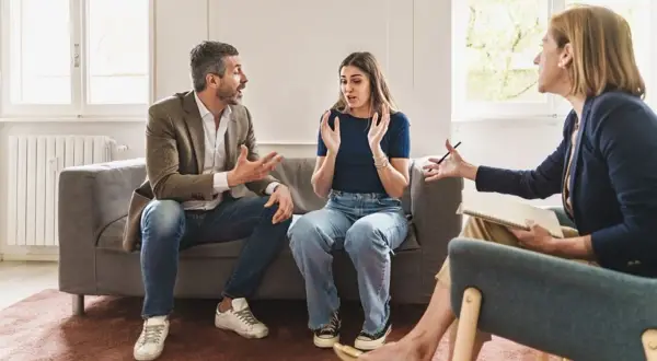 Un couple en thérapie, discutant de problèmes familiaux et d'abus de faiblesse. La thérapeute écoute attentivement.